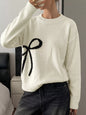 Off-white Bow Graphic Round Neck Sweater by Trendsi, featuring a playful bow print on a cozy knit fabric.