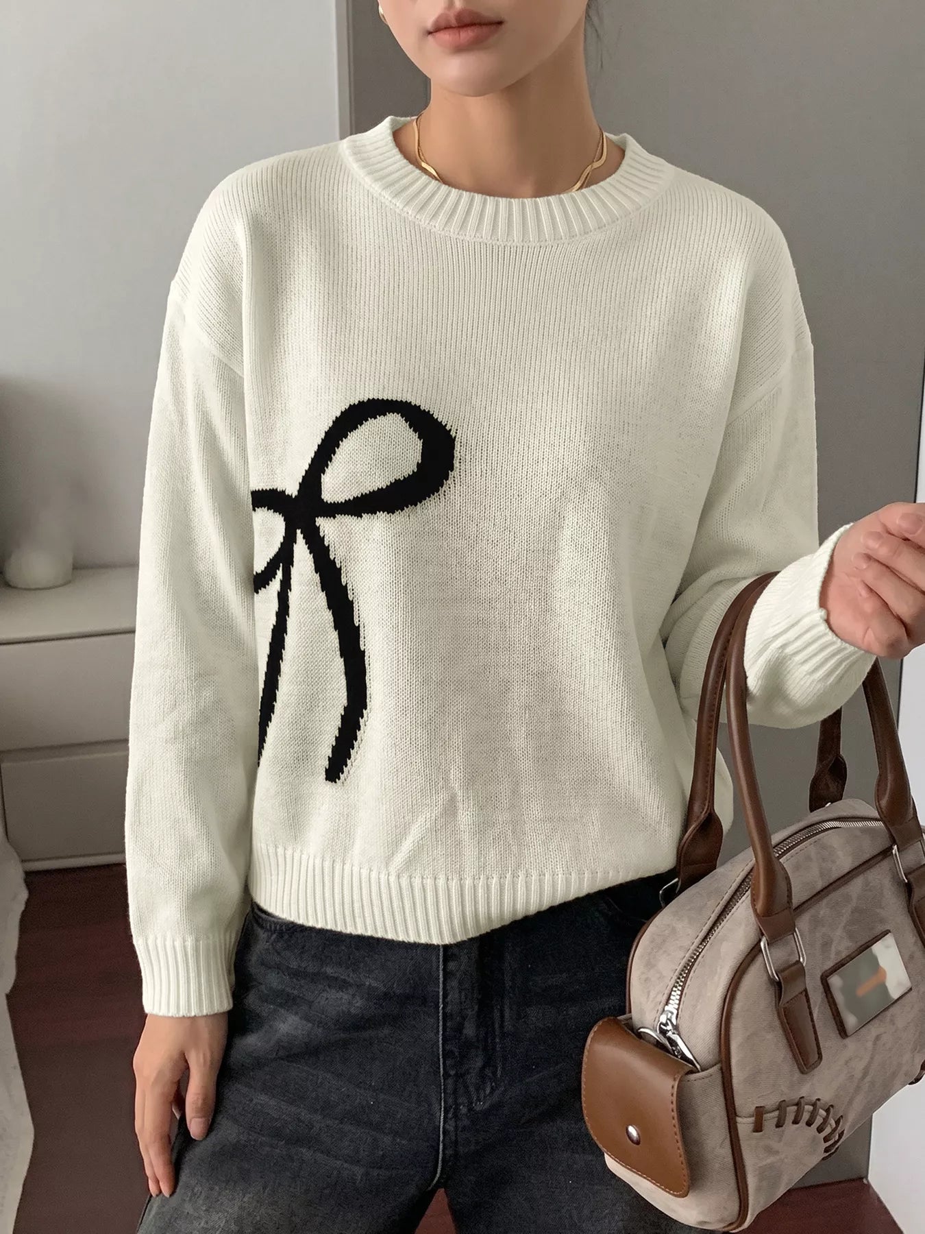 Off-white Bow Graphic Round Neck Sweater by Trendsi featuring a playful bow design on soft knit fabric.
