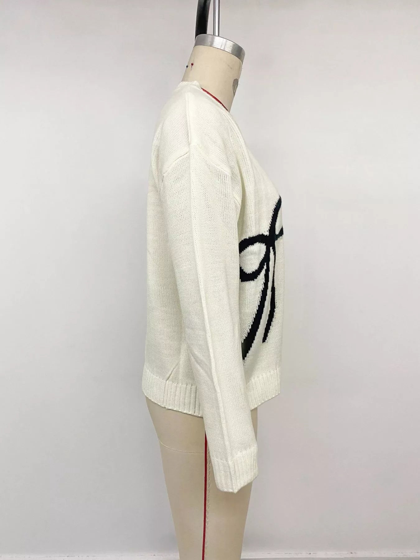 Off-white Bow Graphic Round Neck Sweater by Trendsi featuring a stylish bow print and comfortable fit.