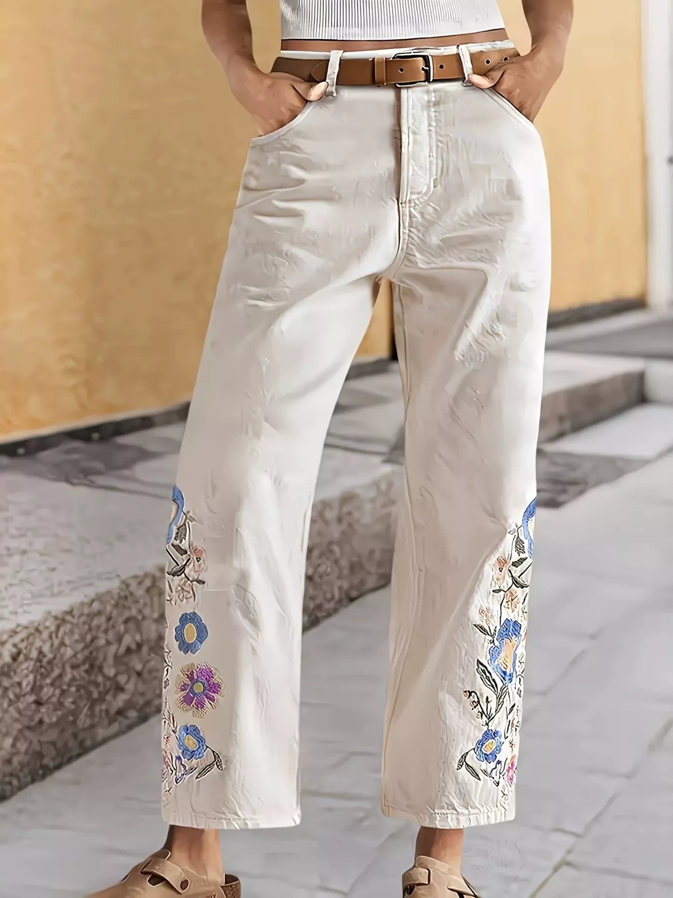 Off-white embroidered floral wide-leg jeans by Trendsi, featuring detailed floral embroidery and relaxed fit.