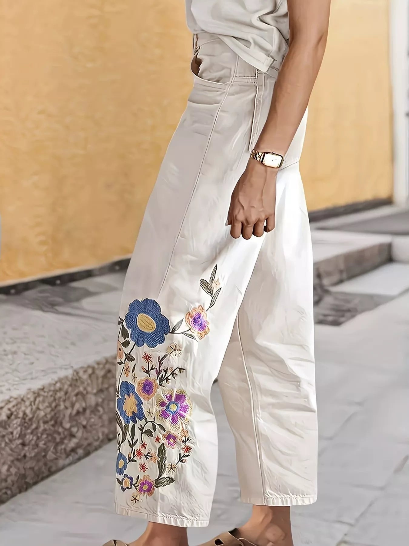Off-white embroidered floral wide-leg jeans by Trendsi featuring intricate floral embroidery and relaxed fit.