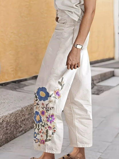 Off-white embroidered floral wide-leg jeans by Trendsi featuring intricate floral embroidery and relaxed fit.