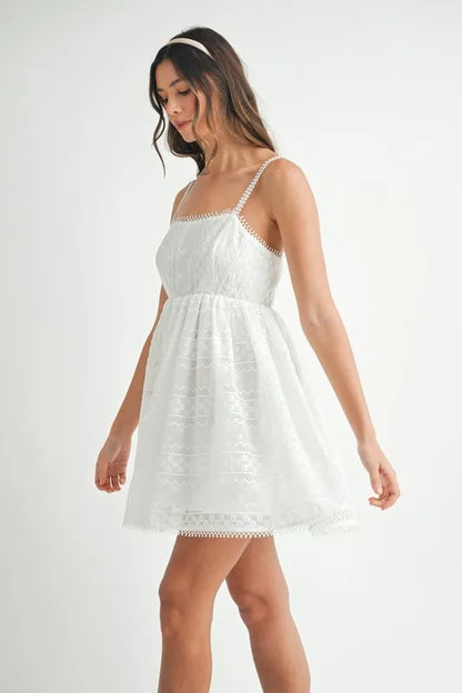 Off-white MABLE eyelet lace babydoll mini cami dress by Trendsi, featuring delicate lace details and a feminine, flowy silhouette.