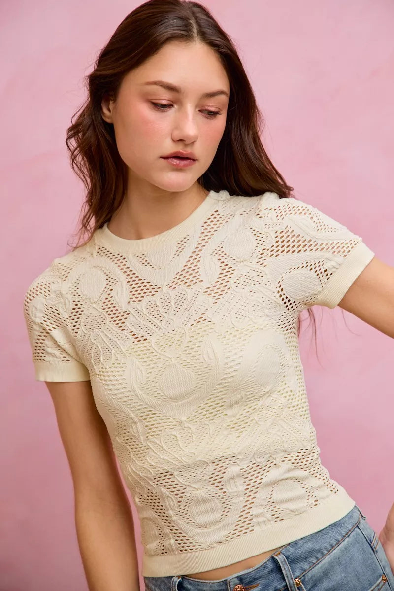 Off-white floral perforated seamless active short sleeve top by Trendsi, showing lightweight, breathable fabric with floral design.