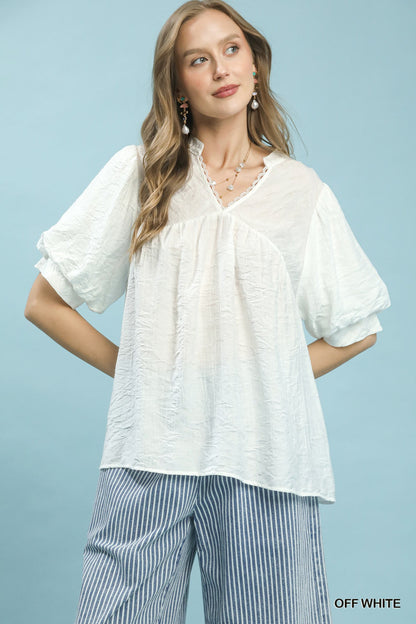 Off-white Umgee textured lace trim V-neck boho blouse by Trendsi, featuring a relaxed fit and intricate lace details.