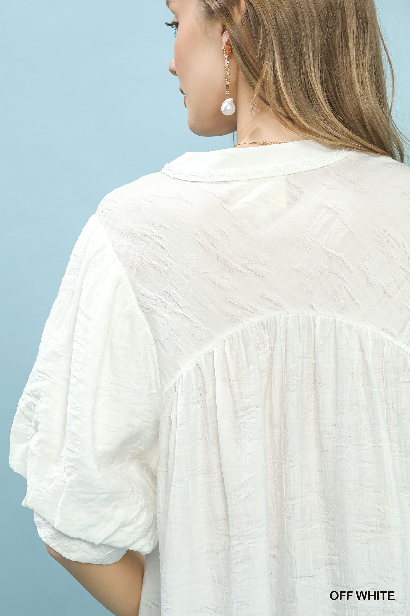 Off-white Umgee boho blouse with textured fabric, lace trim, and V-neck design, featuring a relaxed, bohemian style.