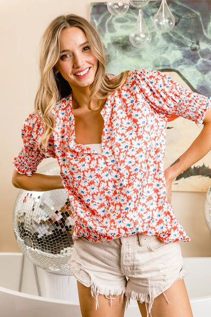 Orange floral V-neck top with smoked puff sleeves from Trendsi, featuring a stylish and feminine design.