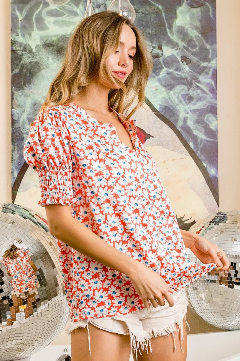 Trendsi BiBi Floral Jqd smoked puff sleeves V-neck top in orange and floral pattern, featuring puff sleeves and a V-neck design.