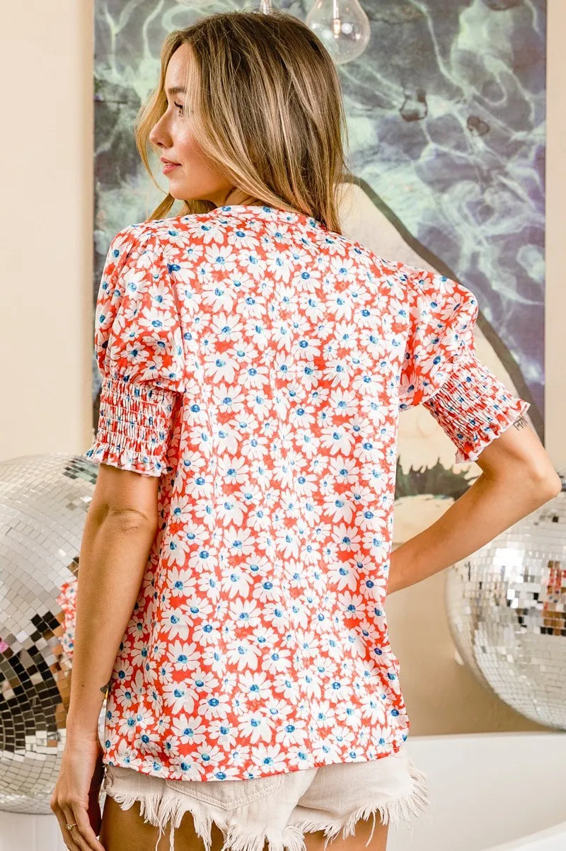 Orange floral V-neck top with smoked puff sleeves from Trendsi, featuring a stylish and feminine design.