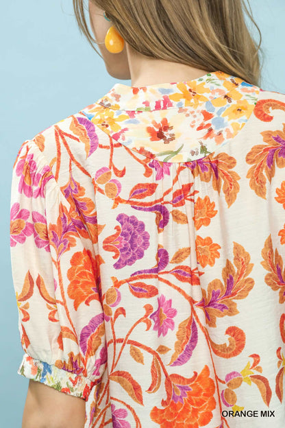 Orange floral split-neck short sleeve top by Umgee with a relaxed fit, featuring a mix of vibrant floral patterns and casual style.