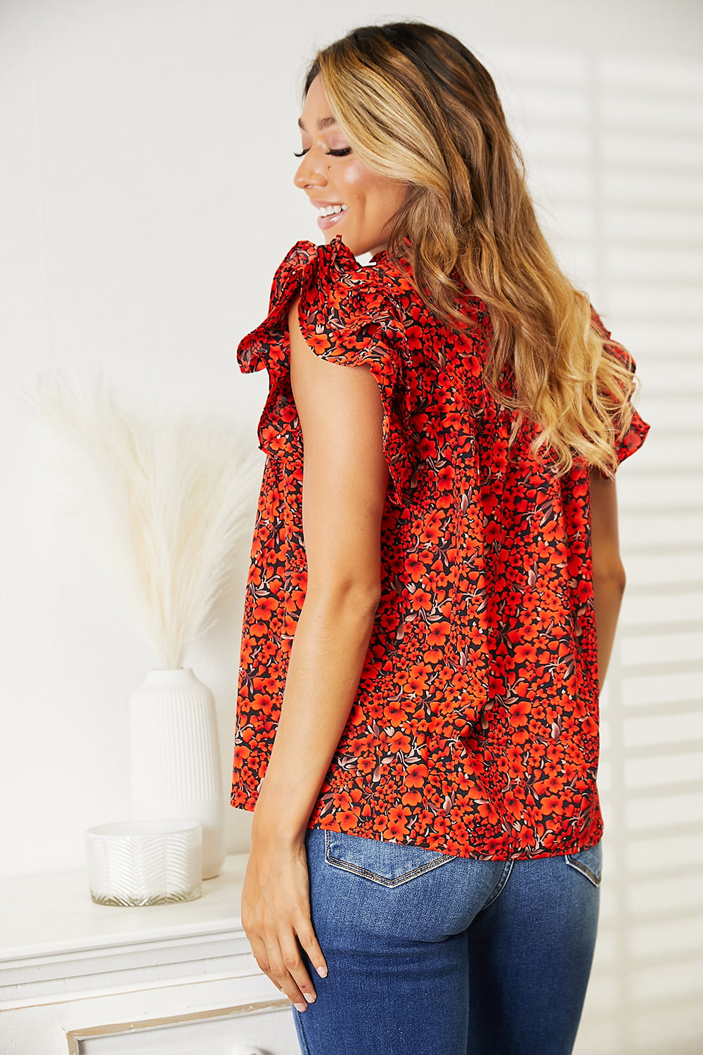 Orange-red floral flutter sleeve blouse with notched neckline from Trendsi, stylish and feminine for casual or dressy wear.