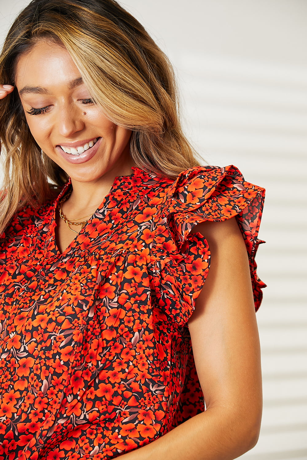 Orange-red floral blouse with flutter sleeves and notched neckline by Trendsi, shown on a model.