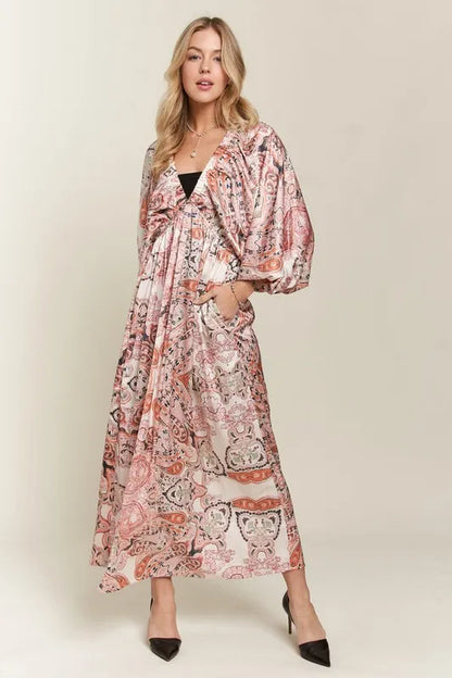 Pale blush ADORA printed V-neck batwing sleeve dress by Trendsi, featuring a flowy silhouette and stylish pattern.