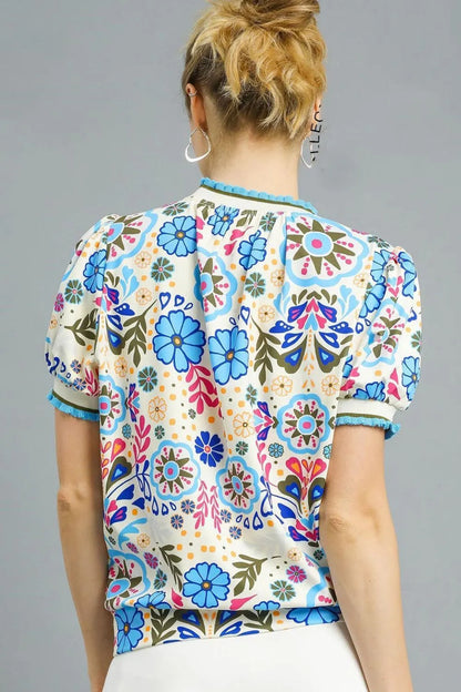 Pastel blue Umgee retro floral puff sleeve top with a relaxed fit, showcased on a white background.