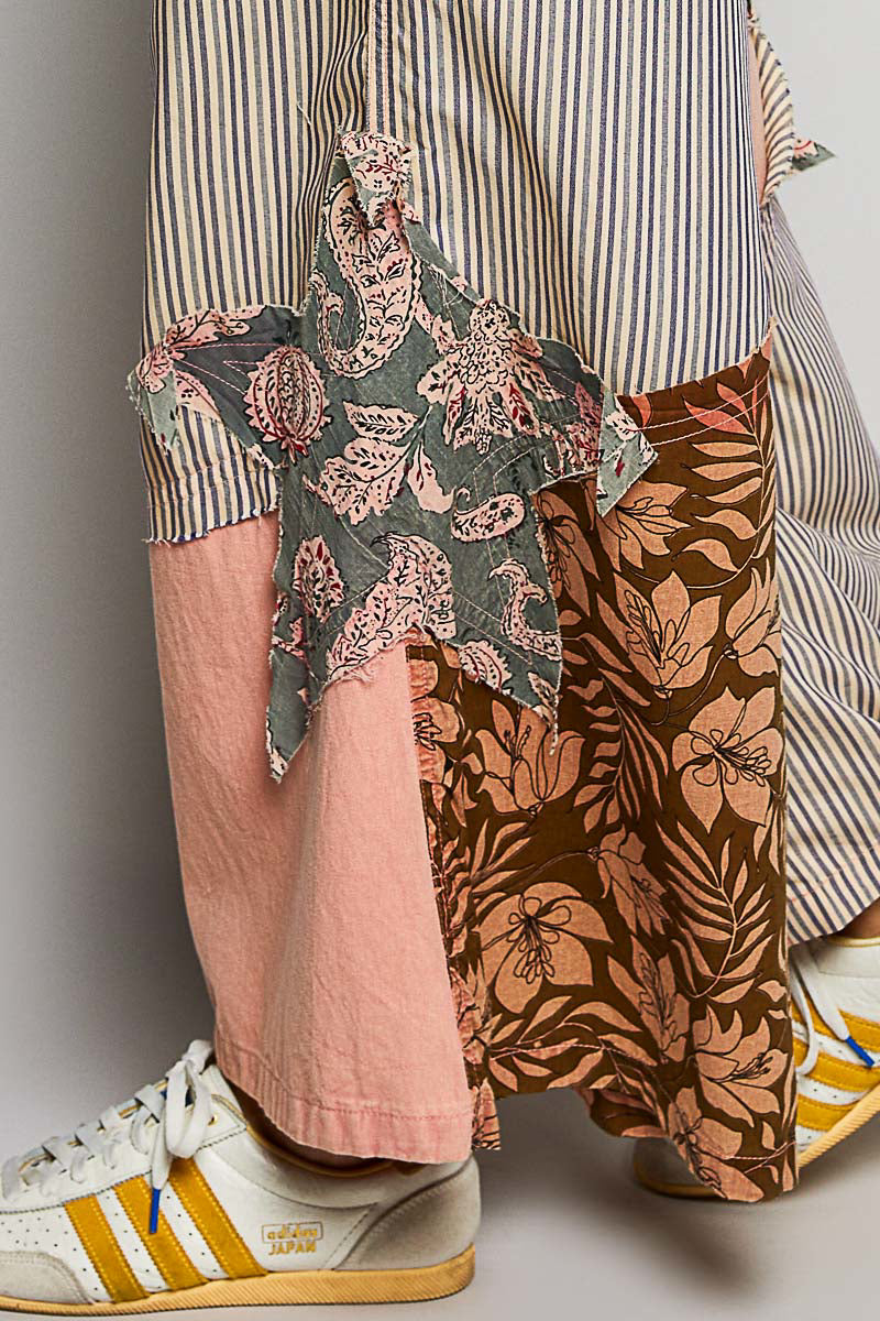 Wide-leg pants with floral patchwork, stripes, and a large star patch on the side, featuring trendy design and vibrant peach color.