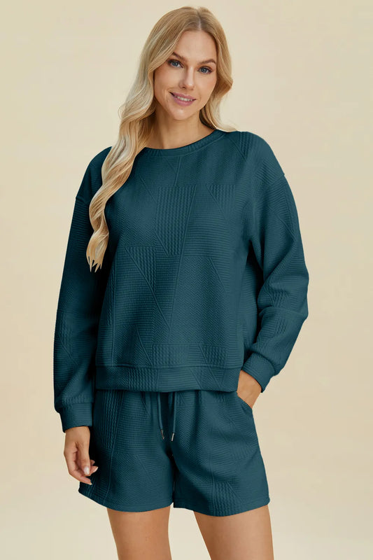 Peacock blue Trendsi Double Take full-size texture round neck long sleeve top and matching shorts set displayed on a hanger.