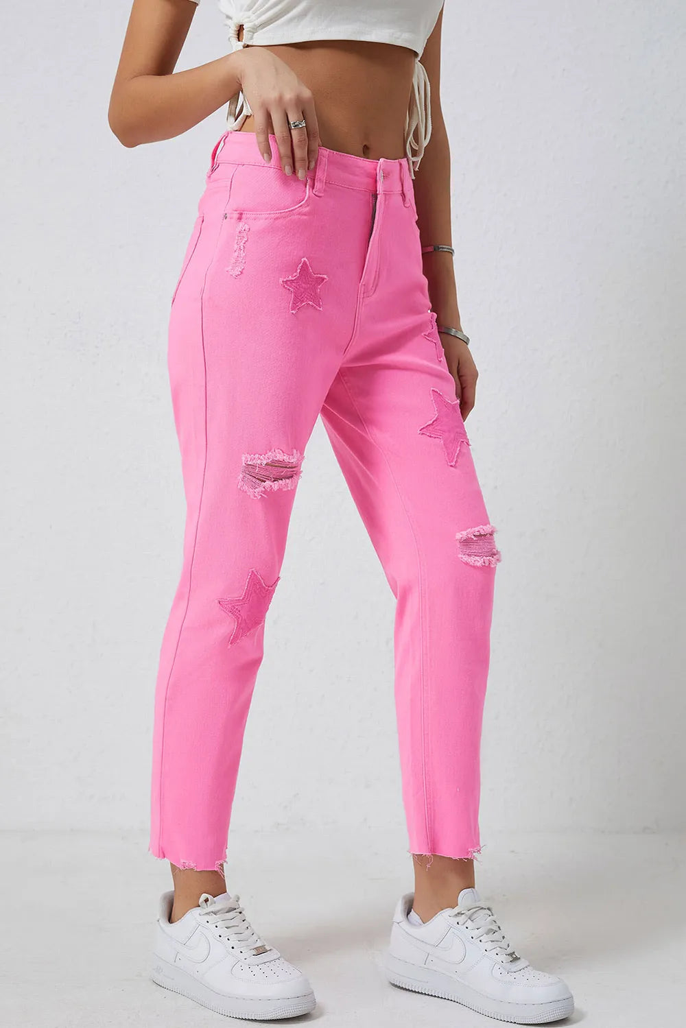 Pink distressed jeans with raw hems from Trendsi, featuring a relaxed fit and distressed detailing.
