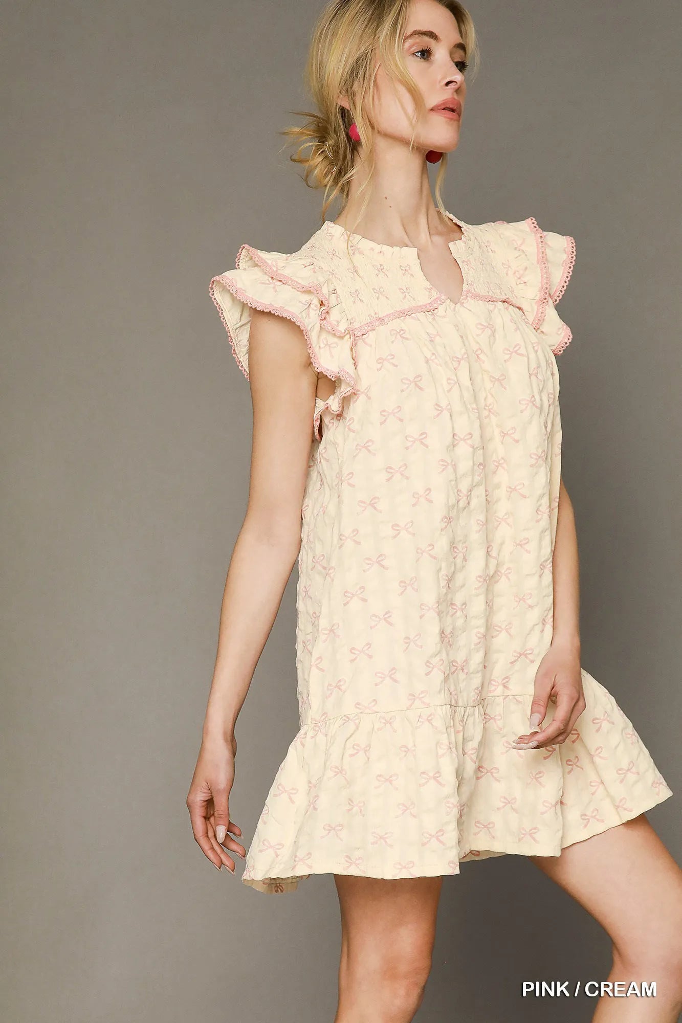Pink and cream Umgee bow print ruffled cap sleeve mini dress with a flattering fit, perfect for casual or semi-formal occasions.