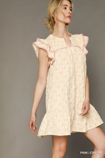 Pink and cream Umgee bow print ruffled cap sleeve mini dress with a flattering fit, perfect for casual or semi-formal occasions.