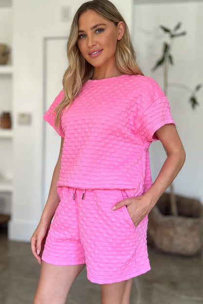 Pink Trendsi Double Take full-size texture T-shirt and shorts set displayed on a hanger, featuring soft fabric and casual style.