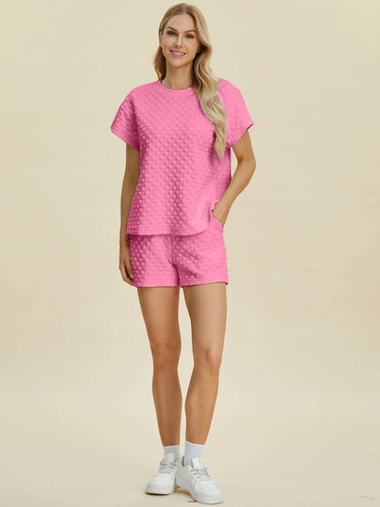 Pink Trendsi Double Take full-size textured T-shirt and shorts set displayed on a model. Casual, comfortable, stylish activewear ensemble.