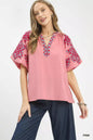 Pink Umgee embroidered sleeve top with contrast trim and relaxed fit, featuring detailed embroidery on the sleeves.