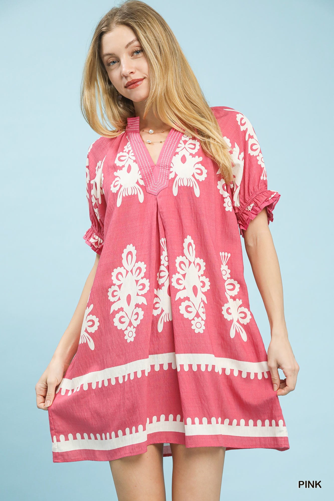 Pink Umgee two-tone border print mini dress with short sleeves, displayed on a hanger against a neutral background.