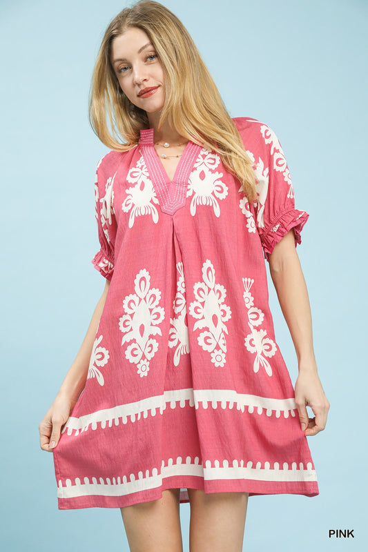 Pink Umgee two-tone border print mini dress with short sleeves, displayed on a hanger against a neutral background.