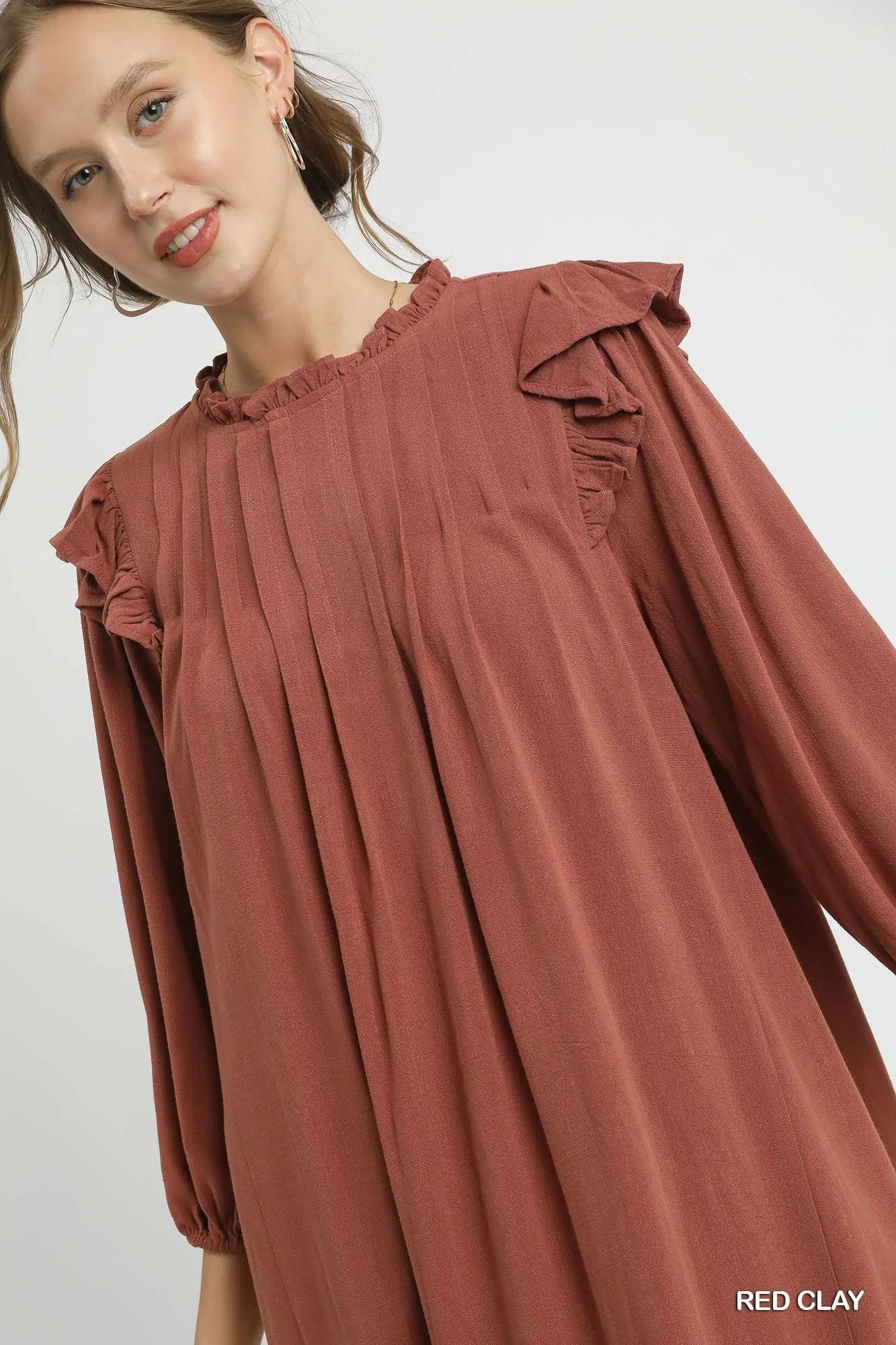 Red clay Umgee linen babydoll dress with ruffle shoulders and pleated skirt, featuring a relaxed, feminine fit.