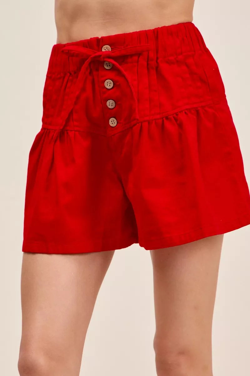 Red Trendsi SO ME solid twill denim pintucked buttoned shorts with waist tie, shown on a model against a neutral background.