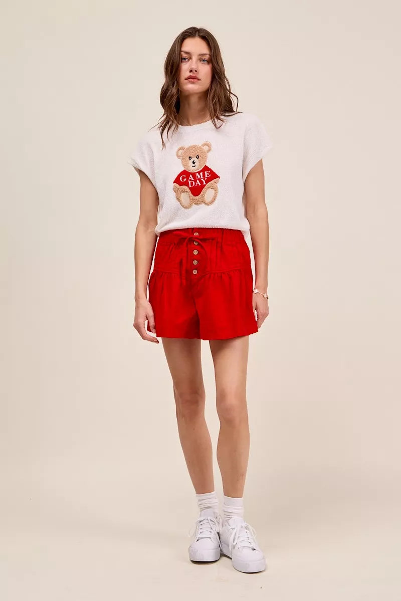 Red SO ME solid twill denim shorts with pintuck details, button closure, and waist tie, styled with casual summer fashion.