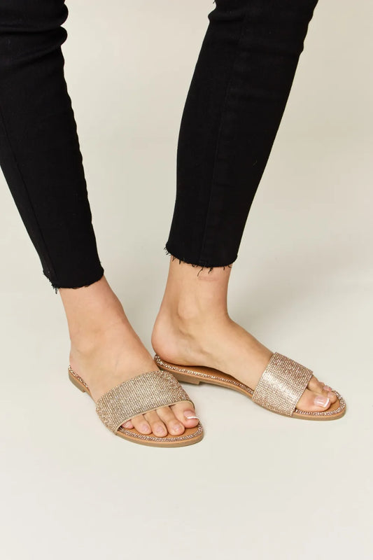 Rose gold WILD DIVA rhinestone open toe flat sandals by Trendsi, featuring sparkling rhinestones and a comfortable flat sole.