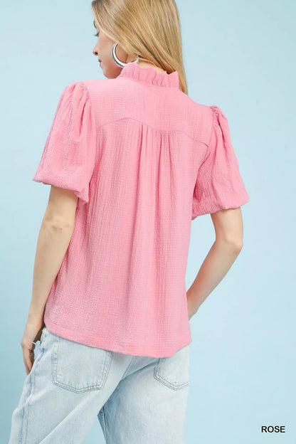 Pink Umgee seersucker puff sleeve blouse with a relaxed fit and ruffled cuffs, styled on a hanger.