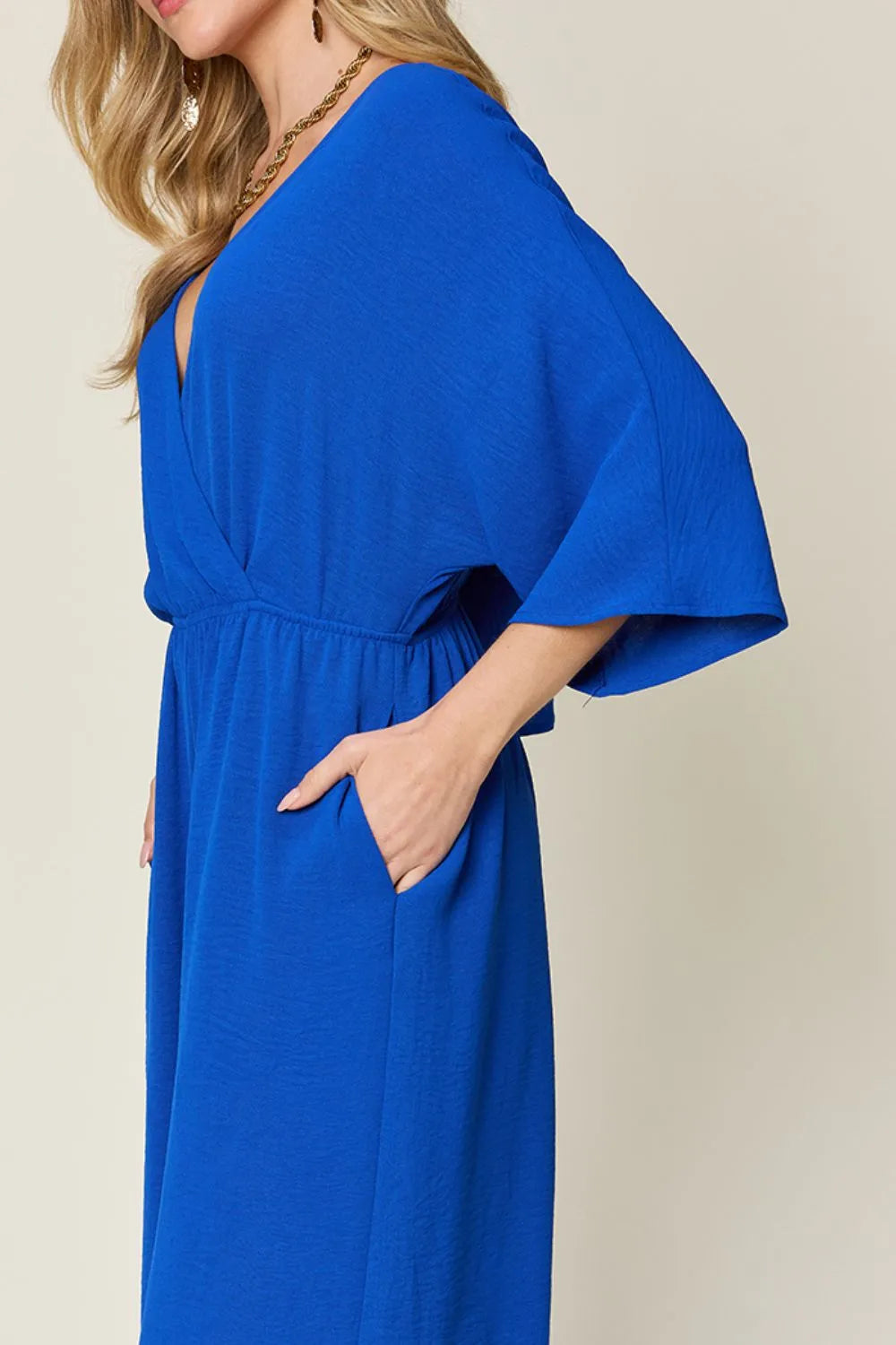 Royal blue Trendsi Double Take full-size surplice jumpsuit with wide-leg design and pockets, displayed on a hanger.