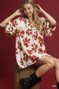 Rust-colored Umgee two-tone floral tie-neck babydoll dress by Trendsi with a flowy silhouette and floral pattern.