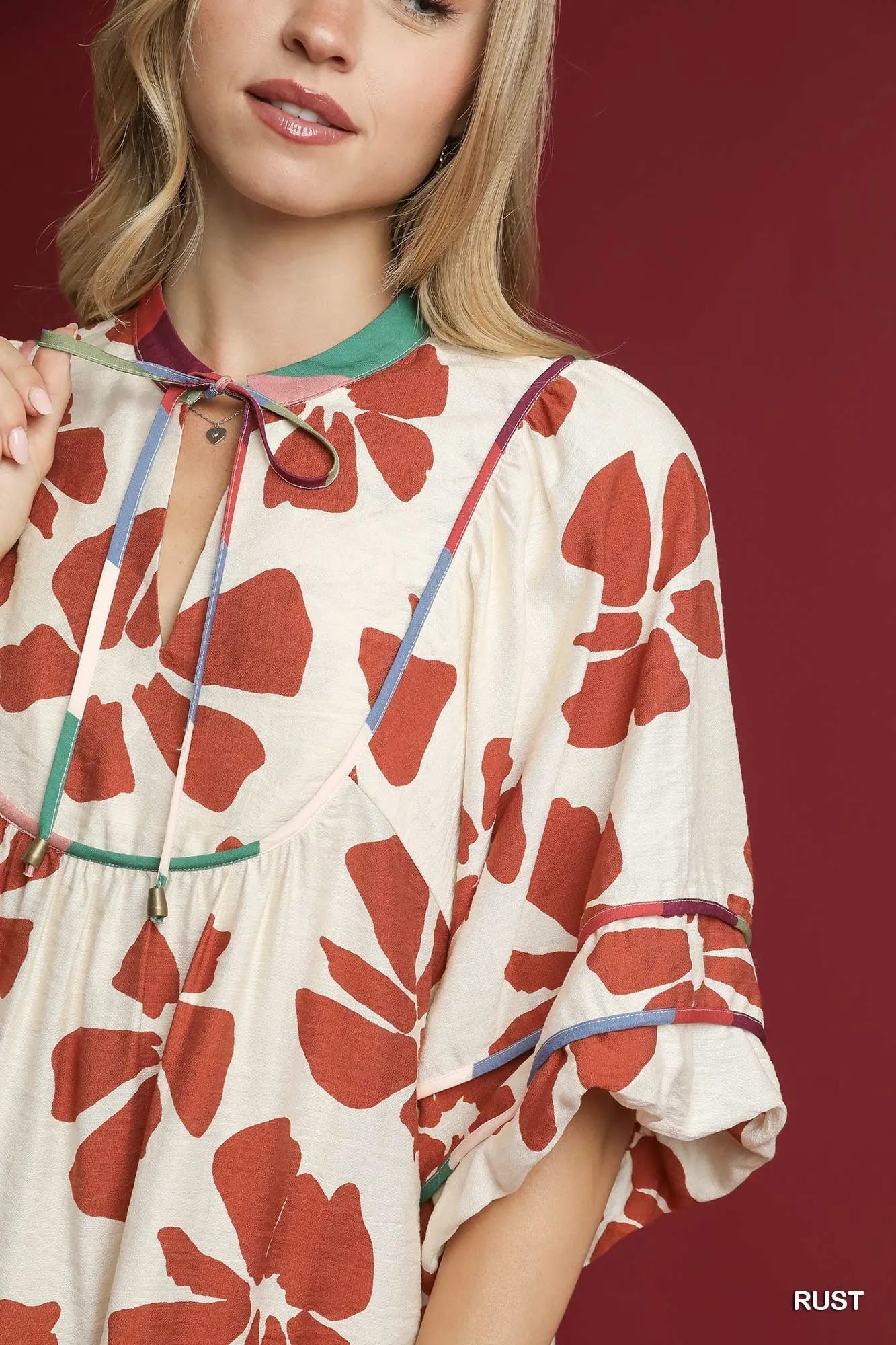 Rust-colored Umgee floral tie-neck babydoll dress with two-tone design, featuring a relaxed fit and feminine floral pattern.