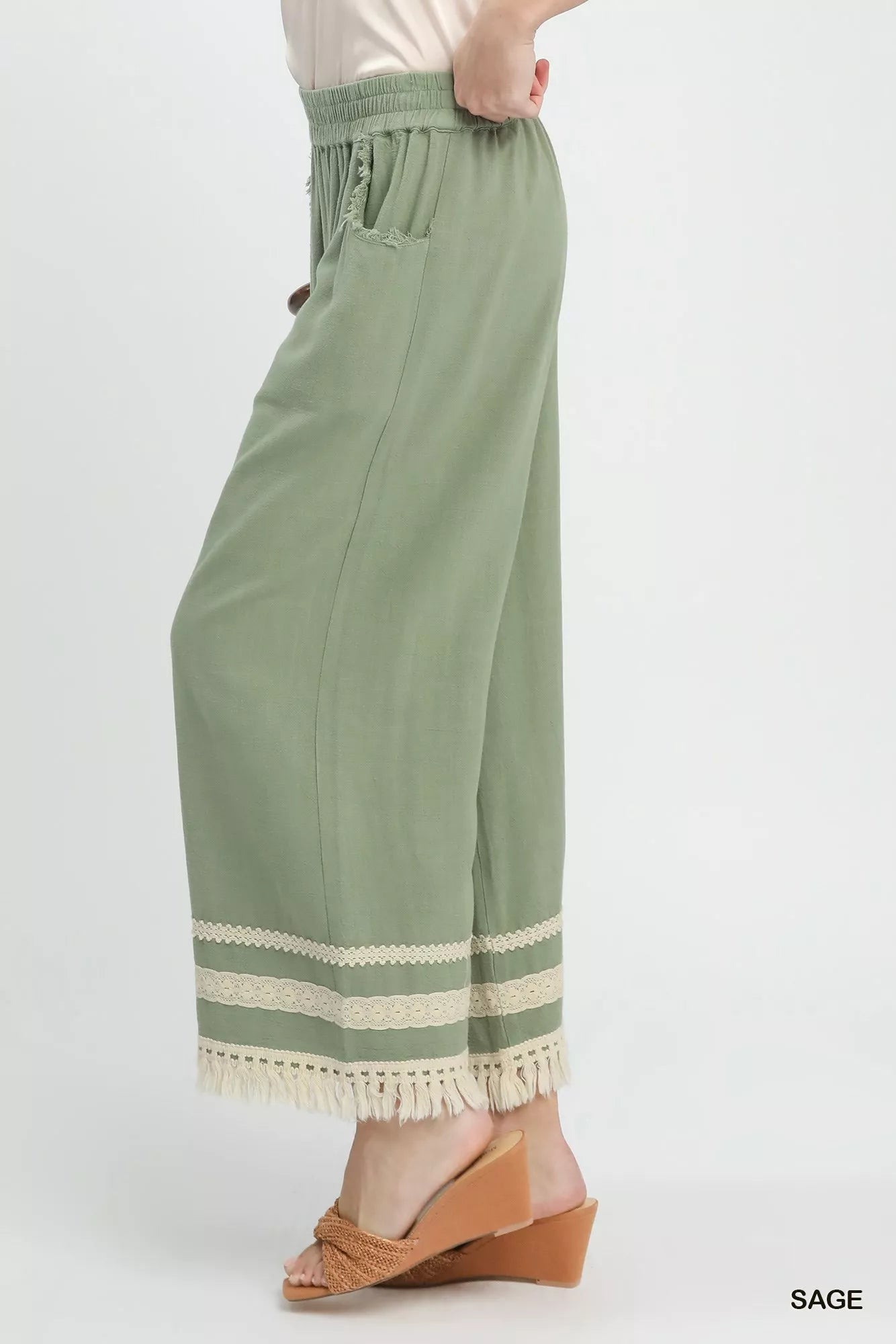 Sage green Umgee lace trim fringe hem wide-leg pants by Trendsi with flowing fabric and stylish design.