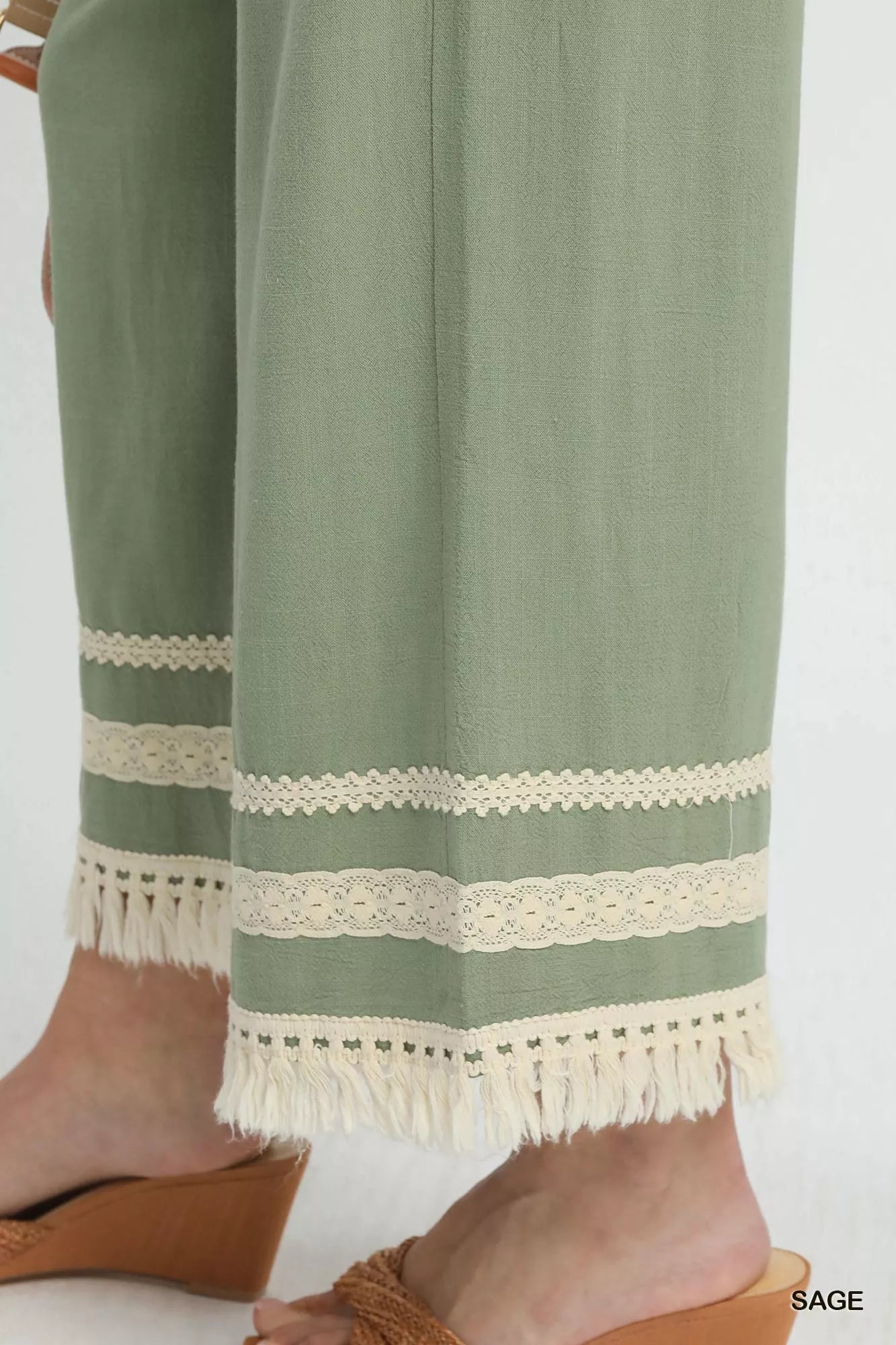 Trendsi Umgee sage wide-leg pants with lace trim and fringe hem, featuring a relaxed fit and stylish design.
