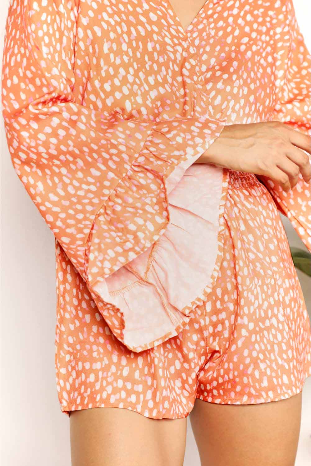 Tangerine double take printed flare sleeve surplice romper by Trendsi, featuring a stylish wrap design and flowy sleeves.