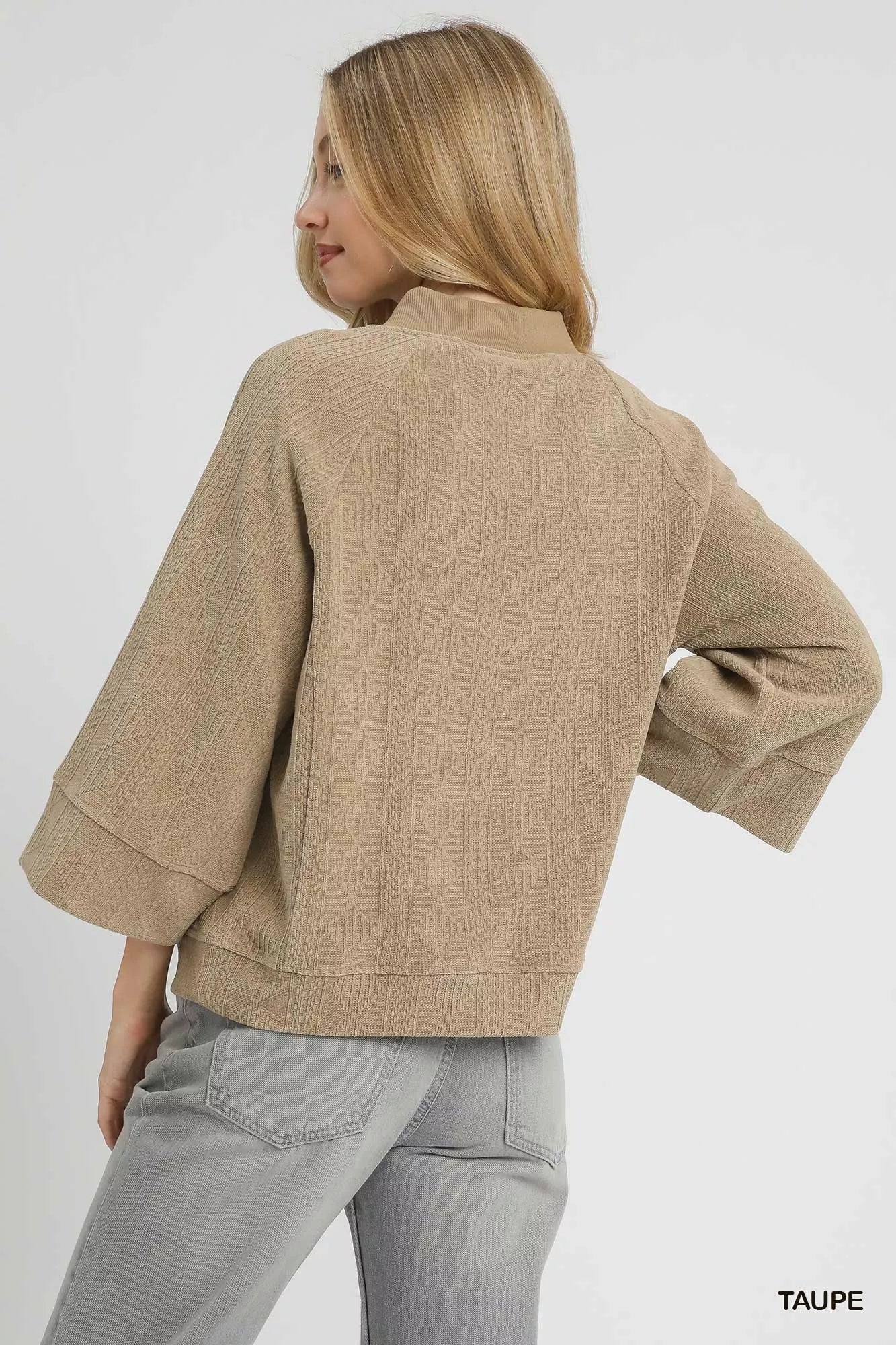 Taupe Umgee textured knit V-neck top from Trendsi, showcasing a close-up of the soft, woven fabric and V-neck design.