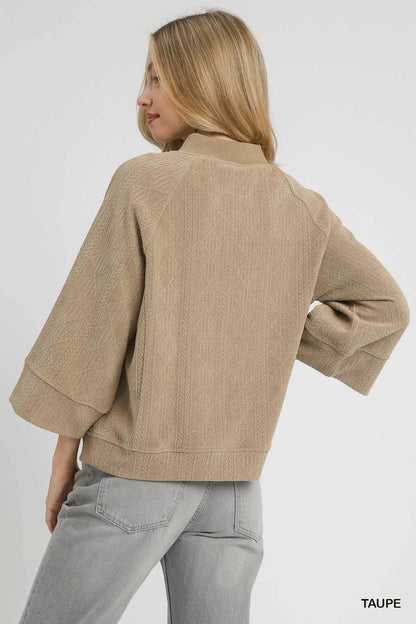 Taupe Umgee textured knit V-neck top from Trendsi, showcasing a close-up of the soft, woven fabric and V-neck design.