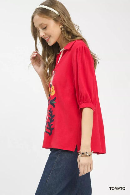 Trendsi Umgee mixed media V-neck print blouse with a colorful floral pattern and relaxed fit, displayed on a hanger.