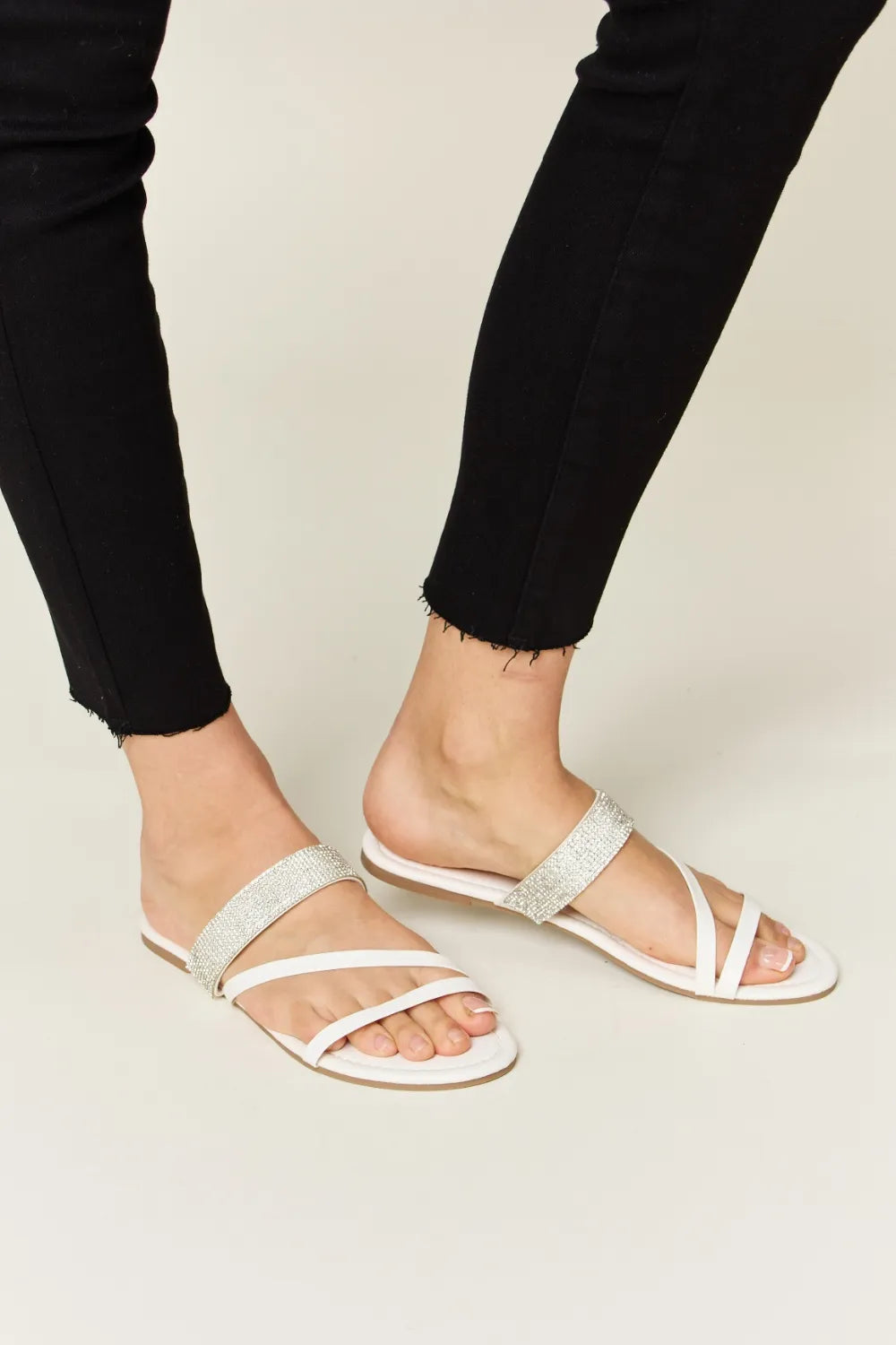 White Wild Diva rhinestone strappy flat sandals with multiple thin straps and rhinestone embellishments for a stylish summer look.