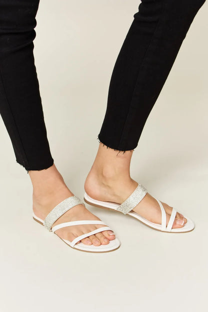 White Wild Diva rhinestone strappy flat sandals with multiple thin straps and rhinestone embellishments for a stylish summer look.