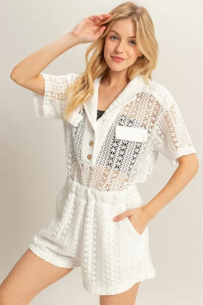 White HYFVE crochet button-front short sleeve romper with a relaxed fit, featuring a stylish V-neck and short sleeves.