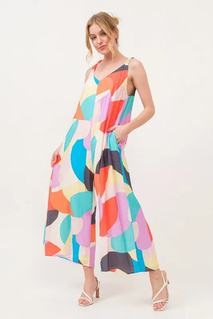 Yellow multi-color geo print jumpsuit with tied shoulder straps and wide-leg design from Trendsi's And The Why collection.
